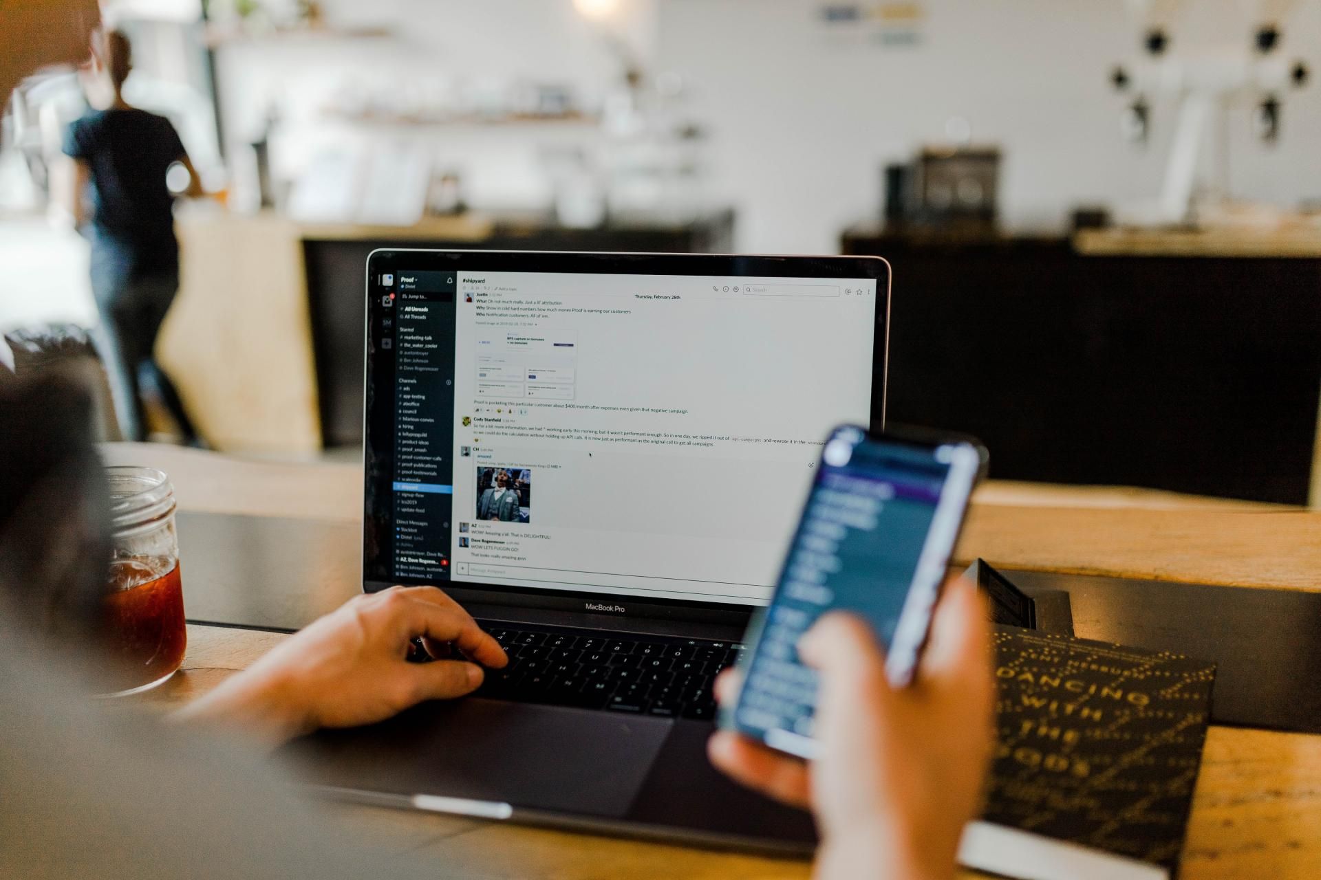 Person using a laptop and holding a phone